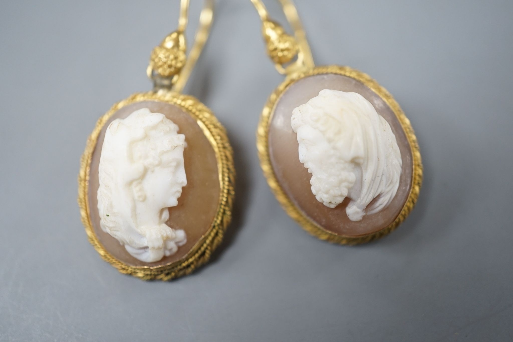 A pair of early 20th century yellow metal and oval cameo shell earrings, carved with a lady to sinister and a gentleman to dexter, overall 40mm, gross 6.2 grams.